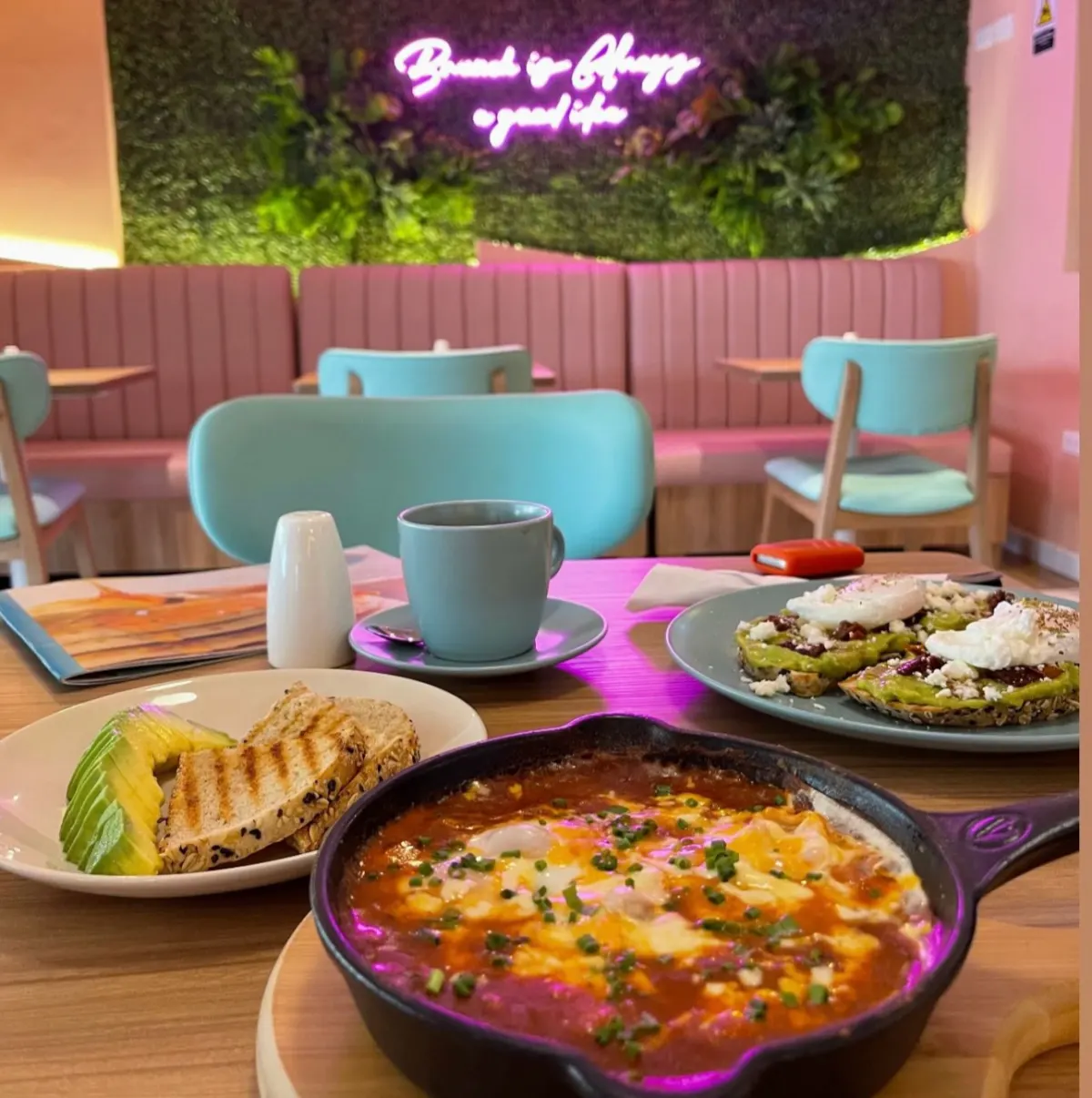 Brunch dishes, including a skillet of baked eggs and toast, on a table in Brunch & Lunch's pink dining room