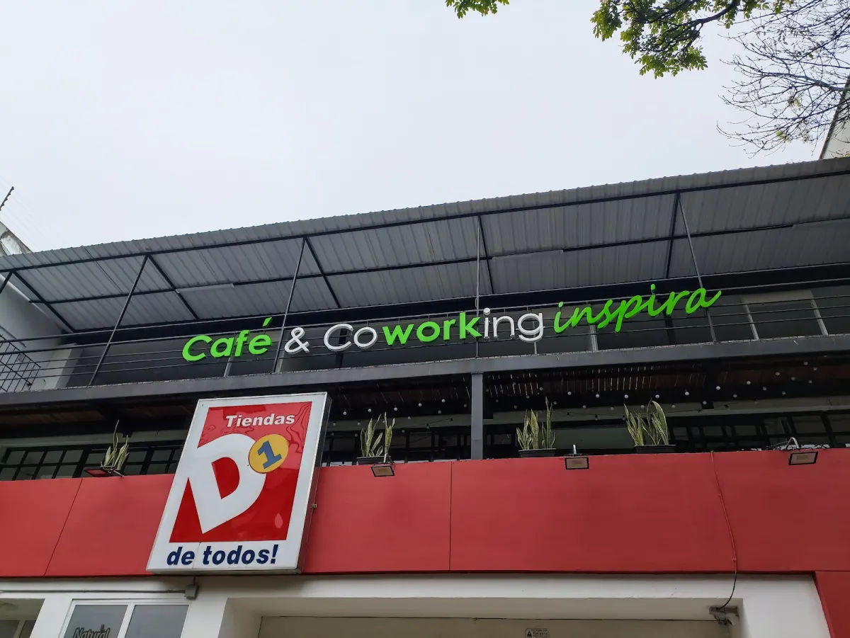 The green Café & Coworking Inspira sign along the upper floor of a building on Avenida Nutibara, above a red D1 shop front
