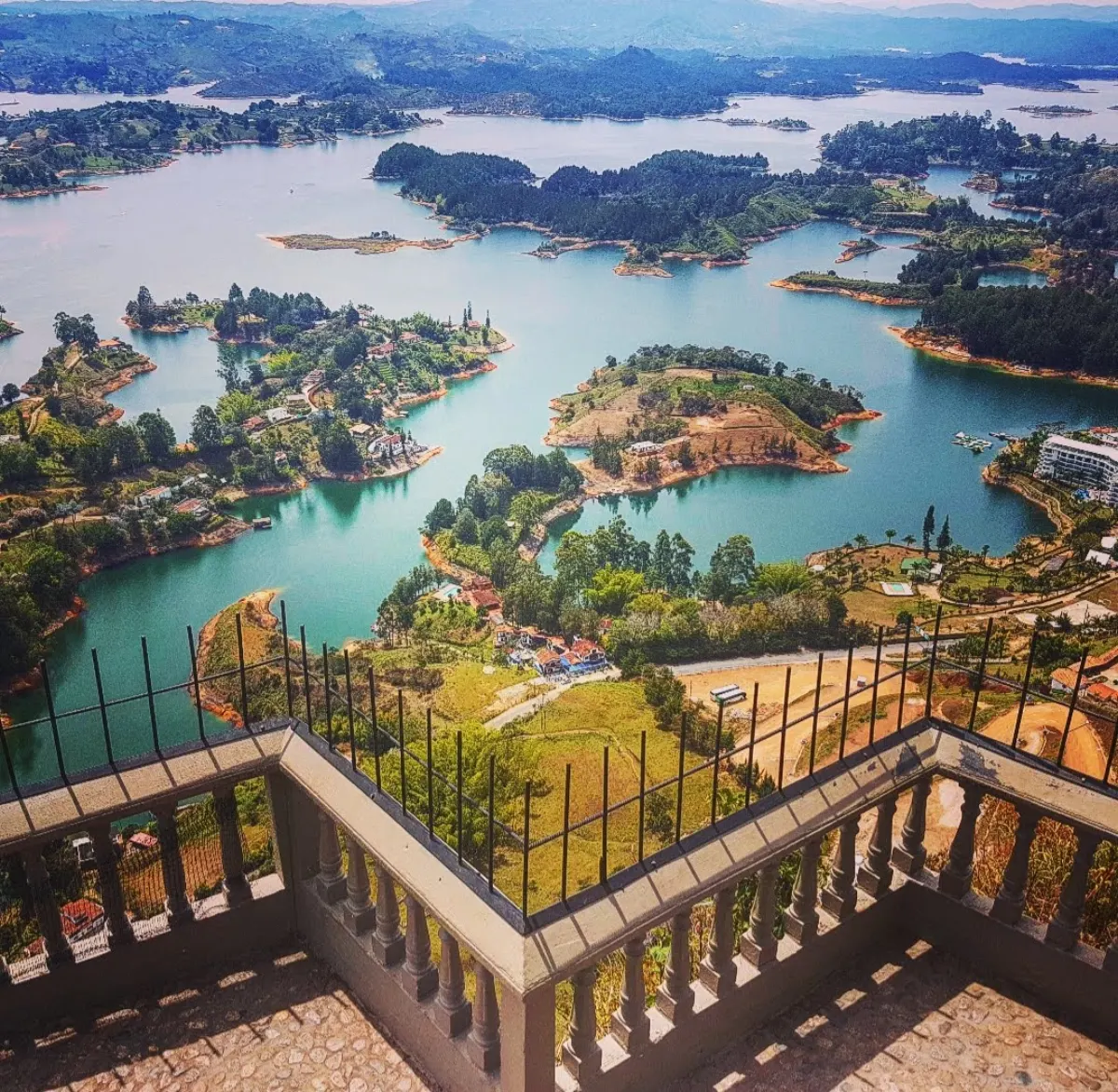 The view from a balustraded terrace on top of El Peñón de Guatapé, looking down on the reservoir's turquoise water and wooded islands