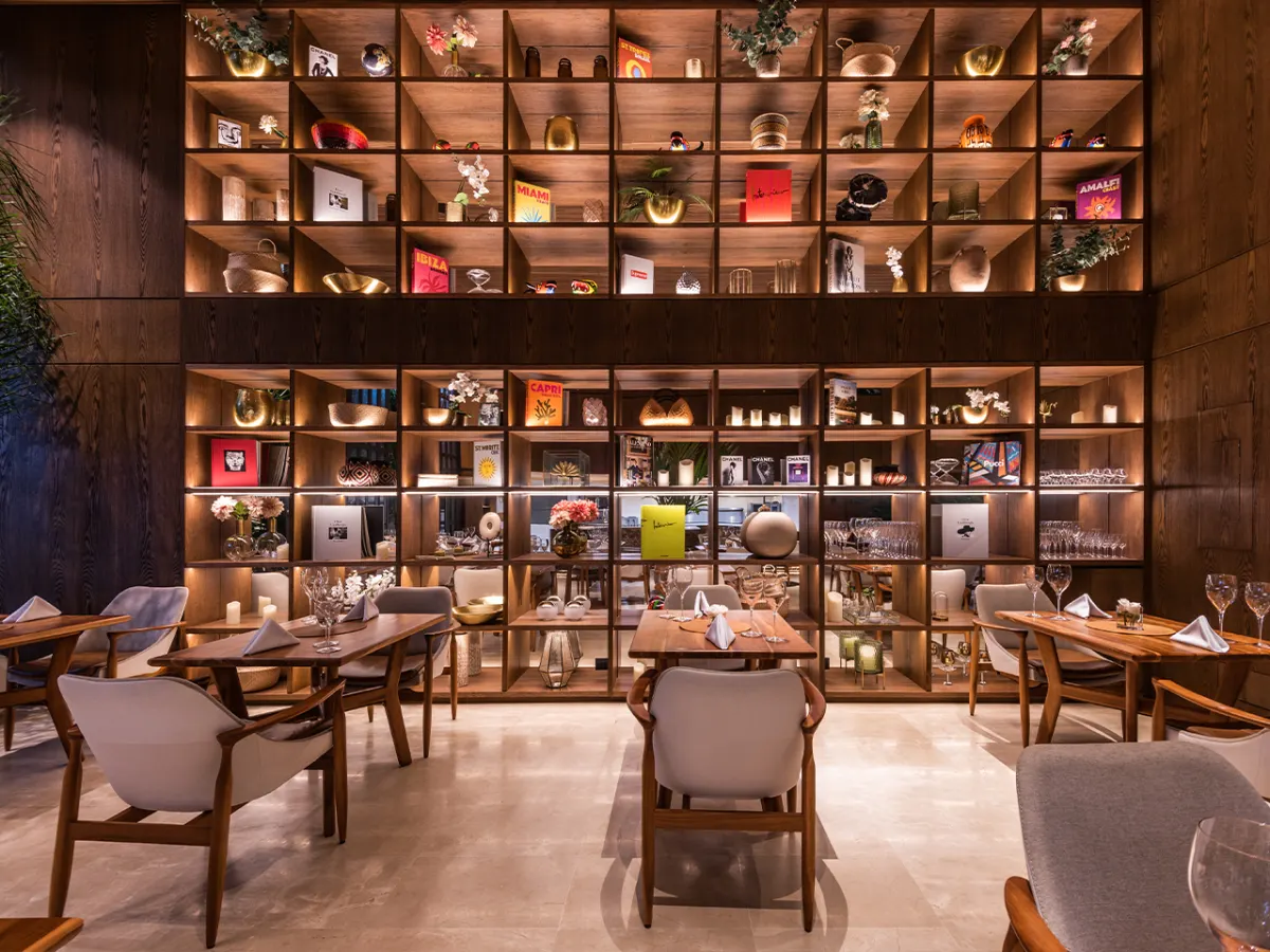 A dining room at Elcielo Medellín with bookshelves lining the walls and set tables