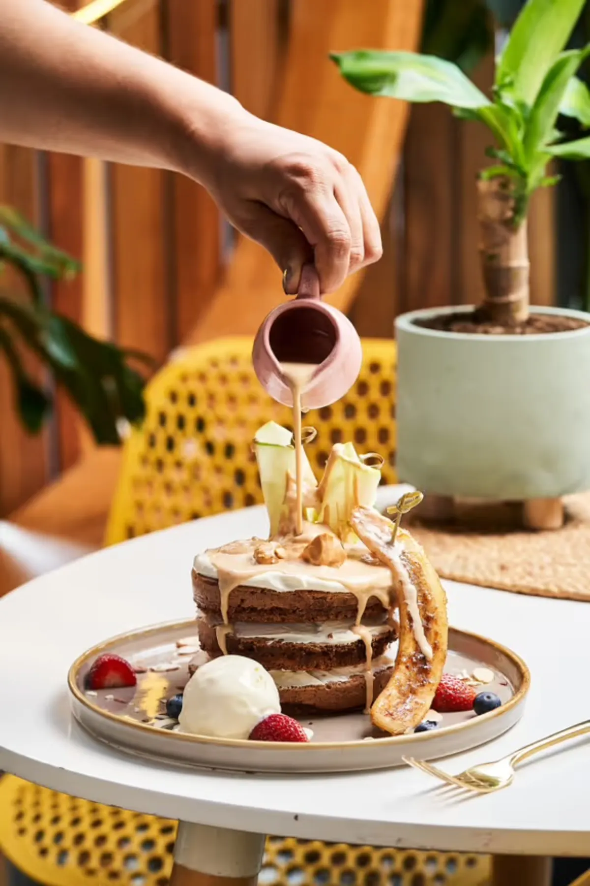 Syrup being poured over a stack of pancakes at Gardenia Brunch & Coffee