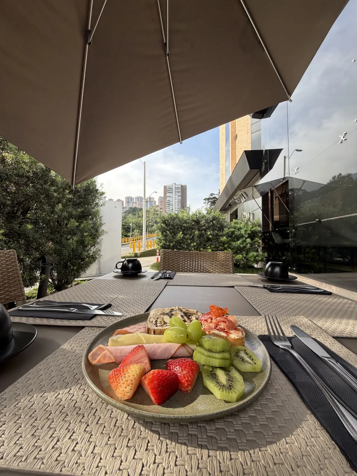 A plate of fruit on La Makha's outdoor terrace, under an umbrella with the city behind