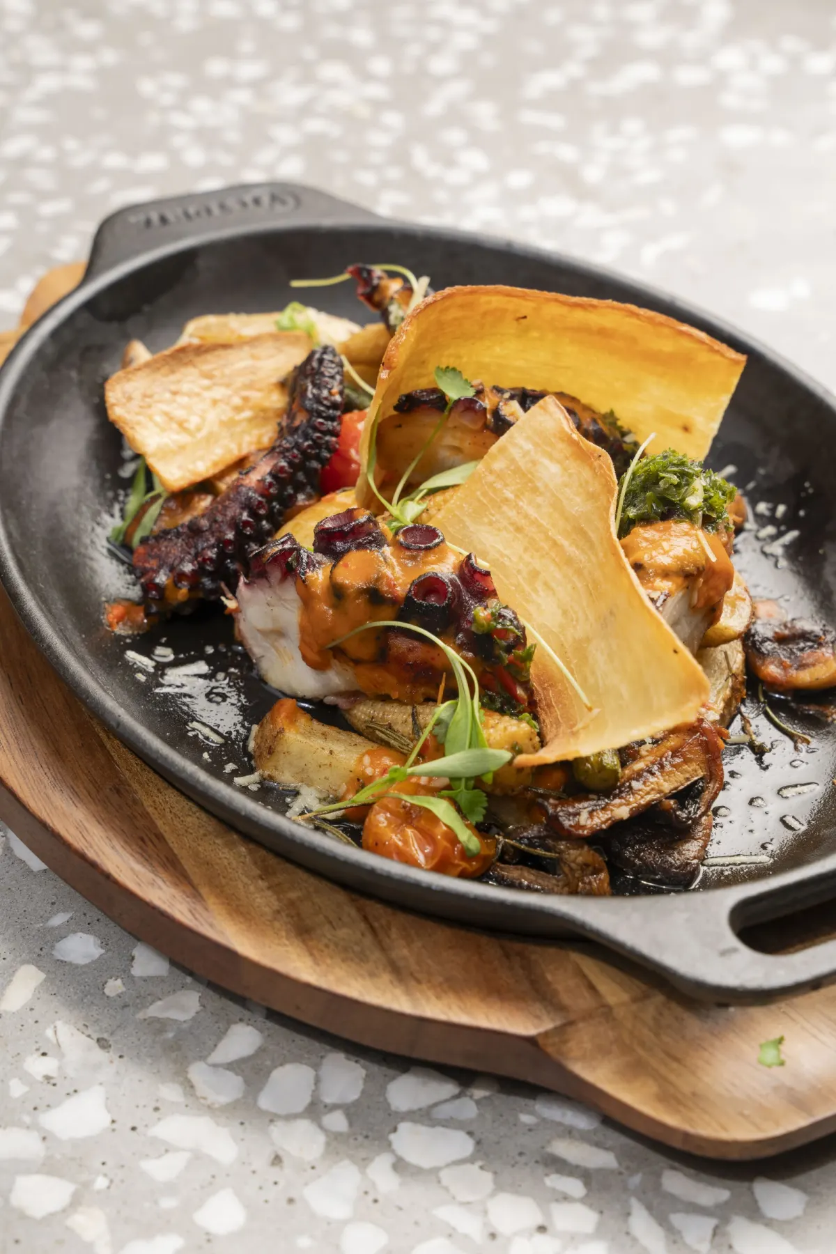 A grilled octopus dish with plantain crisps served in a cast-iron pan at Posada Salsera