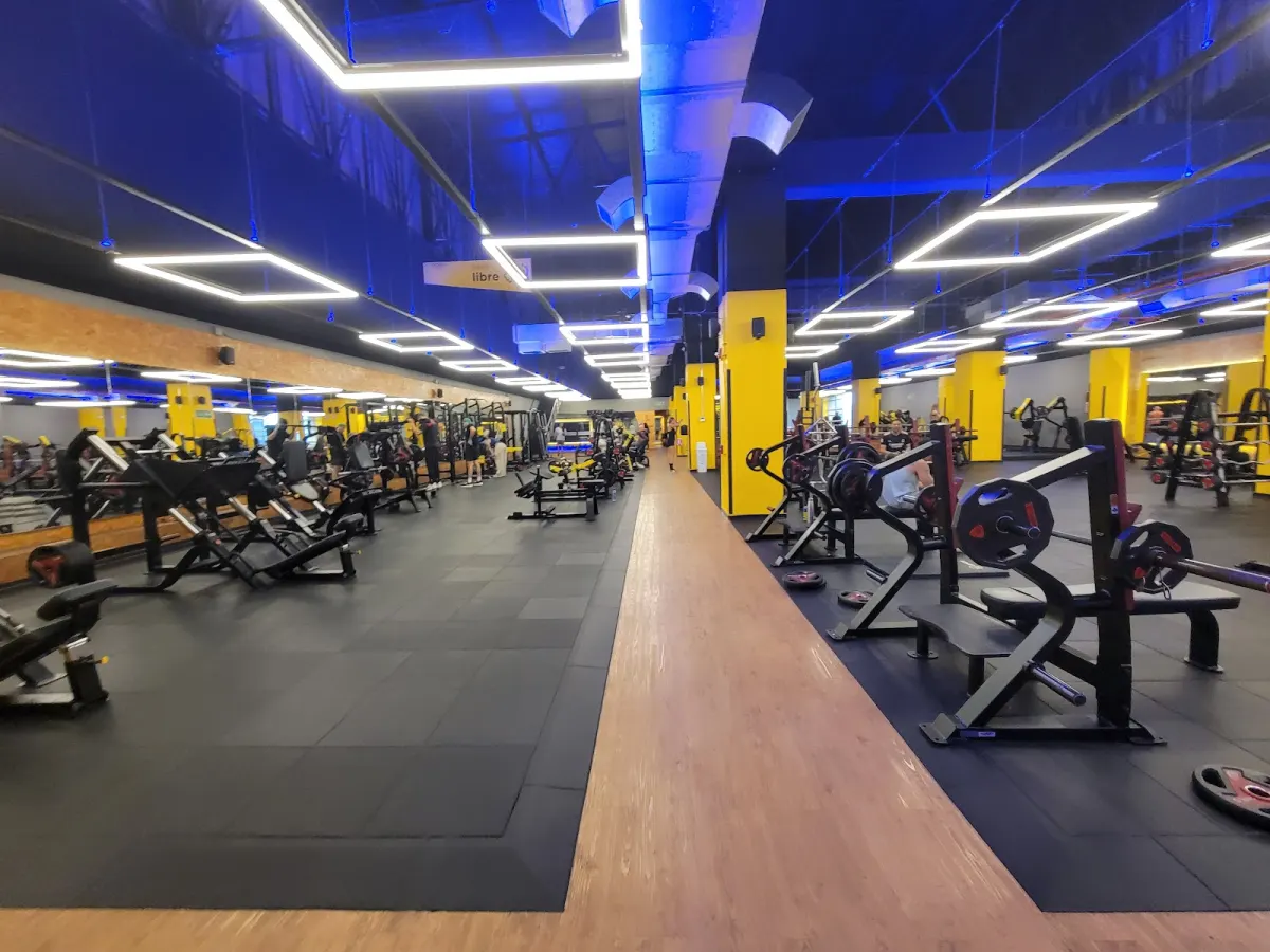 The free weights and strength machine floor at Smart Fit La 10, with yellow pillars and square ceiling lights