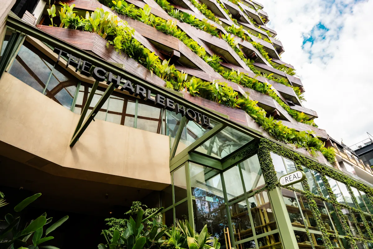 The front of The Charlee Hotel, its name in metal letters over the entrance and planted balconies climbing the tower above